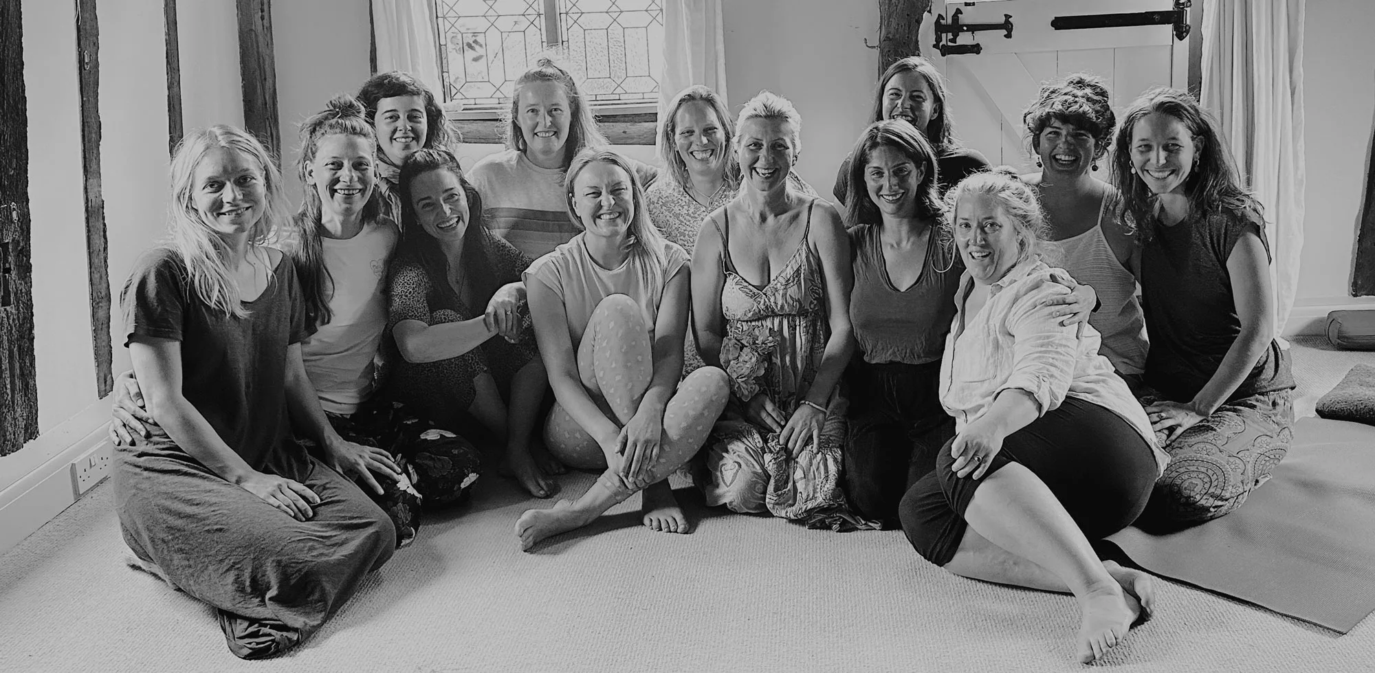 A group of 13 retreat participants sitting together with Eleanor Mann and smiling